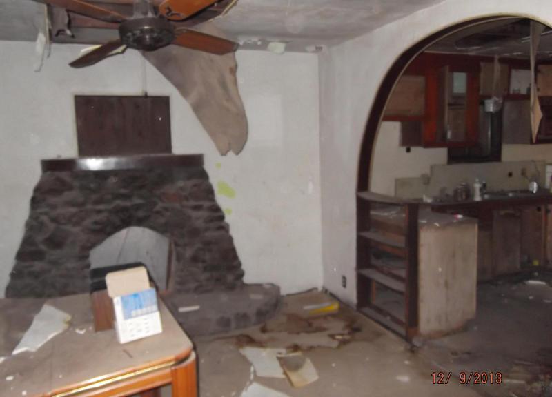 dusty neglected dilapidated living room stone fireplace ceiling damage Eloy Arizona home house for sale real estate photo
